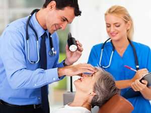 Image of two doctors examining a patient's eye with a flashlight.