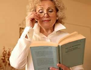 Image of an elderly woman wearing glasses and reading a book.