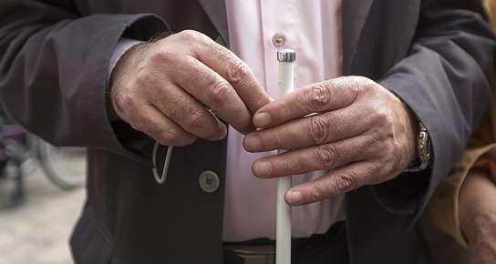 two hands holding white cane